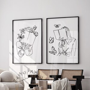 May include: Two framed wall art prints featuring black line drawings on a white background. The left print shows a person holding a book with flowers and butterflies around their head. The right print shows a person reading a book with butterflies.
