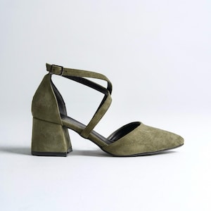 May include: A pair of olive green suede heeled shoes with a criss-cross strap design.