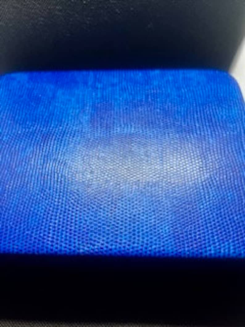 Puede incluir: Una cartera de cuero azul con una superficie texturizada.
