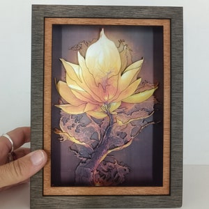 Könnte beinhalten: Ein gerahmtes Kunstwerk mit einer gelben Blume mit filigranen Details vor einem dunklen Hintergrund. Die Blume scheint aus einem Netzwerk von Wurzeln oder Ranken zu wachsen.