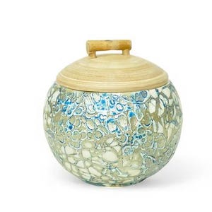 May include: A round ceramic jar with a lid and a bamboo handle. The jar's body has a mosaic pattern in blue, white, and beige. The lid is made of light-coloured wood. The jar is a decorative storage container.