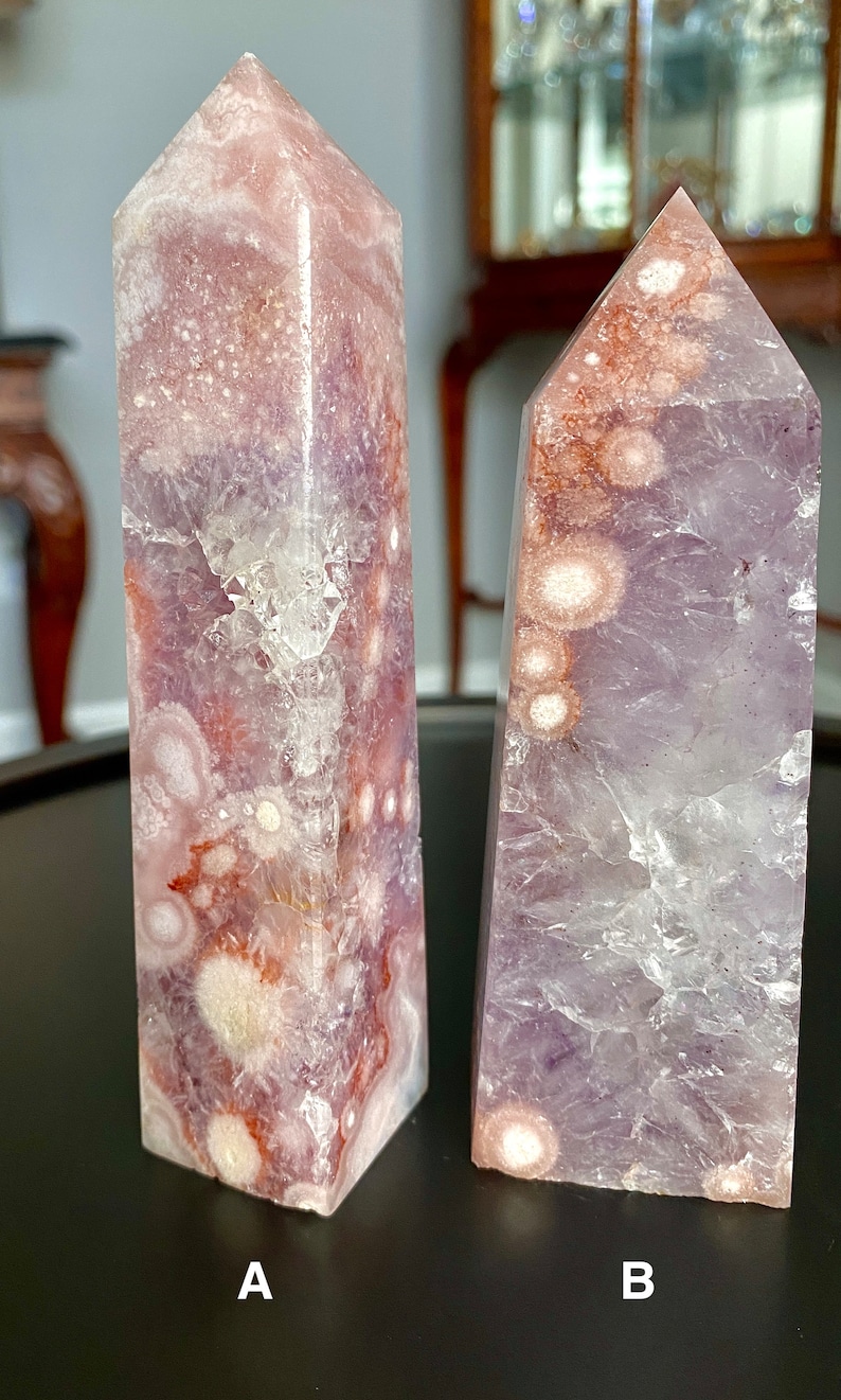 May include: Two amethyst crystal points with a purple and white color pattern. The crystal points are shaped like pyramids and have a smooth, polished surface. The crystal points are labeled A and B.