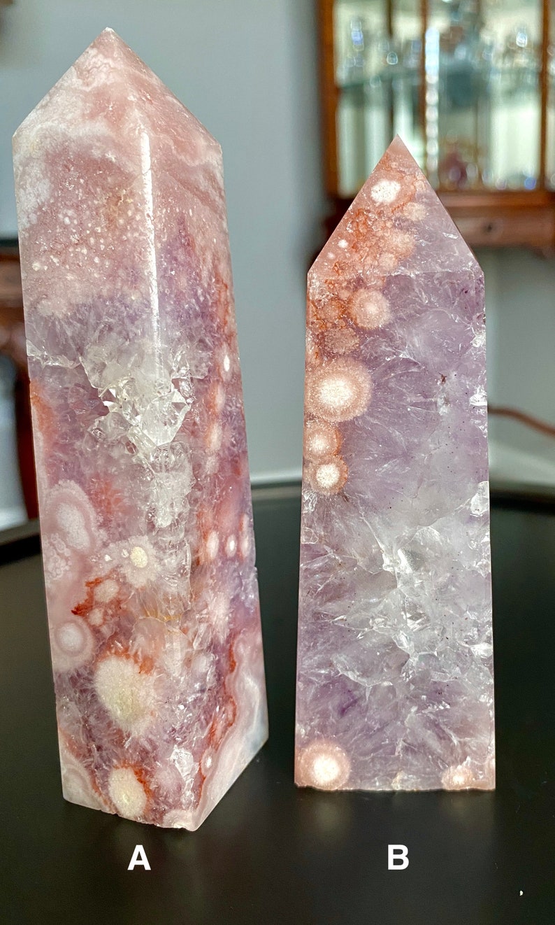 May include: Two amethyst crystal points with white and pink inclusions. The crystal on the left is labeled "A" and the crystal on the right is labeled "B".