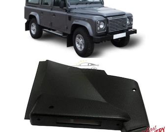 May include: A gray Land Rover Defender SUV is shown above a black car part. The SUV has a boxy design with large tires and a front grille. The black part has a textured surface and a rectangular opening.