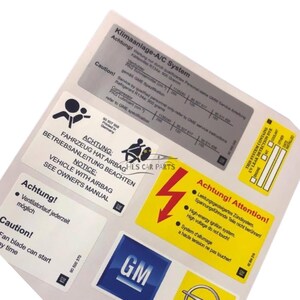 Pode incluir: Um conjunto de autocolantes de aviso e informa&ccedil;&atilde;o para autom&oacute;veis. Os autocolantes apresentam texto em v&aacute;rios idiomas, incluindo alem&atilde;o e franc&ecirc;s, com avisos sobre airbags, alta tens&atilde;o e sistemas de ar condicionado. Os autocolantes t&ecirc;m um log&oacute;tipo GM.