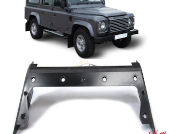May include: A gray Land Rover Defender SUV is shown above a black automotive part. The part is a bracket with multiple circular holes. The vehicle is a four-door model with silver wheels.