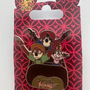 Könnte beinhalten: Disney Pin Trading Around the World Pin mit Figuren aus Splash Mountain. Der Pin zeigt drei animierte Charaktere in einer Logflume-Fahrt. Der Pin befindet sich auf einer rot gemusterten Rückseite mit dem Logo der Disney Parks Collection.
