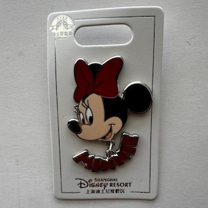 Op de afbeelding: Minnie Mouse emaille pin met een rode strik en de naam "Minnie" in rode letters. De pin is bevestigd aan een witte kaart met het logo van Shanghai Disney Resort.