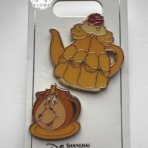 May include: Two enamel pins featuring characters from Beauty and the Beast. One pin is a yellow teapot with a red rose on top. The other pin is a brown teacup with a smiling face. The pins are on a silver backing with the Shanghai Disney Resort logo.