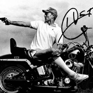 Peut inclure: Photographie en noir et blanc d'un homme sur une moto, pointant un pistolet. L'homme porte un polo blanc, un short, une casquette de baseball et des baskets. La moto a une selle et un réservoir noirs. Une signature est visible.