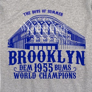 May include: A blue and white graphic design of Ebbets Field, the former home of the Brooklyn Dodgers, with the text "The Boys of Summer" above the stadium and "Brooklyn Dem 1955 Bums World Champions" below.