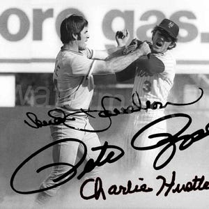 May include: Black and white photograph of two baseball players in action. One player is wearing a baseball cap and a striped jersey with the number 3. The other player is wearing a baseball uniform. The image is signed by several people.