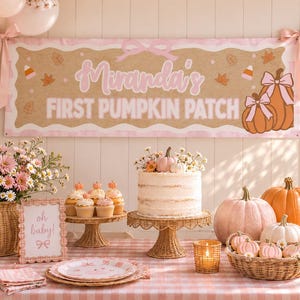 May include: A party banner with the text Miranda's FIRST PUMPKIN PATCH, featuring orange pumpkins with pink bows, autumn leaves, and candy corn. The display includes a white cake, cupcakes, pink and orange pumpkins, and floral arrangements.