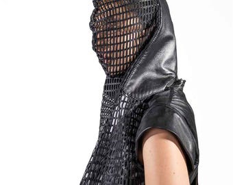 Op de afbeelding: Een zwarte leren capuchon met een geïntegreerd gezichtsmasker gemaakt van een netmateriaal met een rasterpatroon. De capuchon bedekt het hoofd en valt over de borst, terwijl het netgedeelte over het gezicht hangt voor een gestructureerde look.