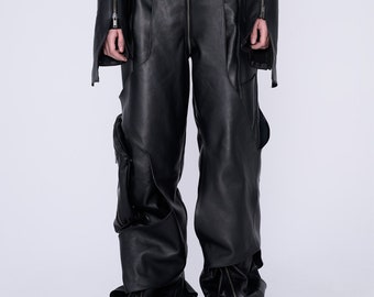 Op de afbeelding: Zwarte leren broek met een hoge taille, een centrale ritssluiting aan de voorzijde, meerdere naaddetails en zijzakken. De zoom van elke broekspijp is voorzien van een verticale ritssluiting, wat zorgt voor een los, wijdvallend silhouet.