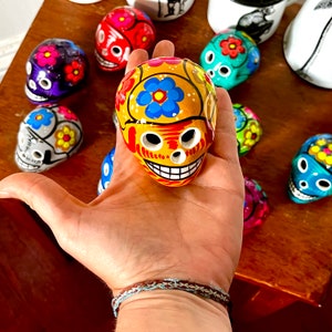 May include: A selection of brightly coloured ceramic sugar skulls, hand-painted with floral designs. The skulls are in various colours, including yellow, red, blue, and green. These decorative skulls are a vibrant addition to any collection.