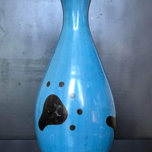 Op de afbeelding: Een blauwe keramische vaas met een zwarte rand en zwarte potafdruk-ontwerpen.