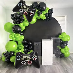Op de afbeelding: Een zwarte en groene ballonboog met een zwart-witte 'Epic Birthday!' gamecontrollerballon. De boog is versierd met zwarte en groene ballonnen en een zwarte achtergrond.