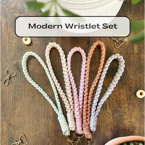 May include: Set of five colorful crocheted wristlets with gold keychains. The wristlets are in shades of green, pink, orange, and gray.  Modern Wristlet Set.