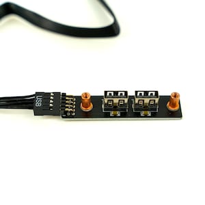 May include: A black USB 2.0 port panel with two USB ports and copper-coloured standoffs. The panel has a connector labelled "USB" and a series of pins for connecting to a computer.