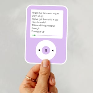 May include: A light purple sticker in the shape of a music player. The screen displays song lyrics: "You've got the music in you, Don't let go, You've got the music in you, One dance left, This world is gonna pull through, Don't give up."