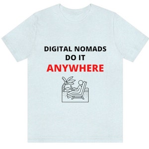 May include: Light blue t-shirt with the text "DIGITAL NOMADS DO IT ANYWHERE" in black and red. A black and white illustration of a person sitting on a beach chair with a laptop.