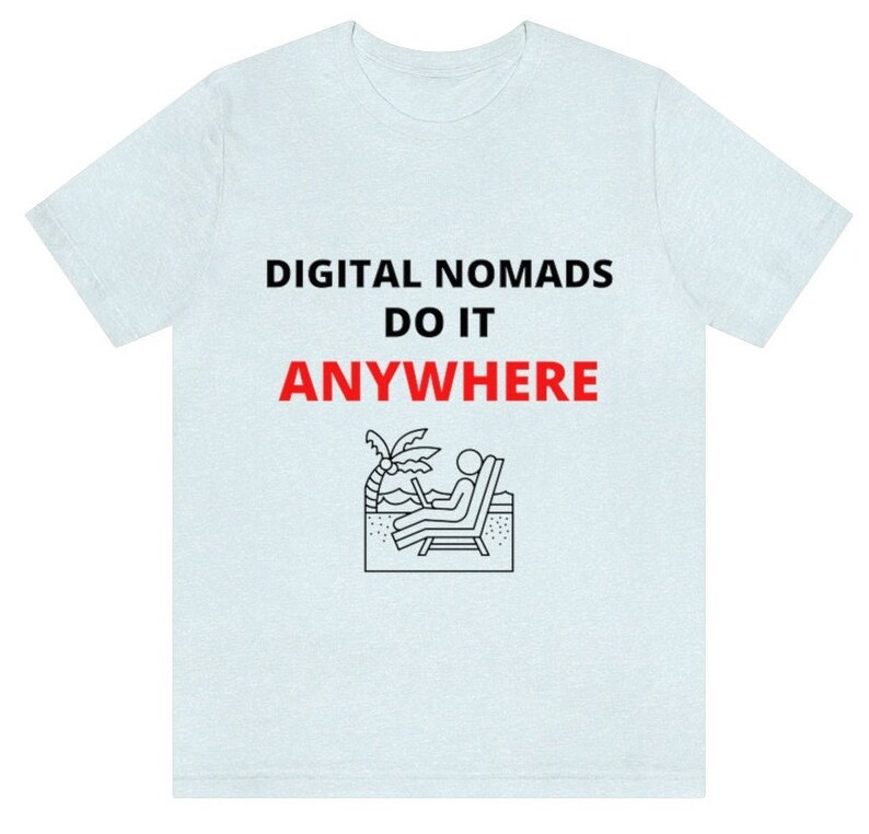 May include: Light blue t-shirt with the text "DIGITAL NOMADS DO IT ANYWHERE" in black and red. A black and white illustration of a person sitting on a beach chair with a laptop.