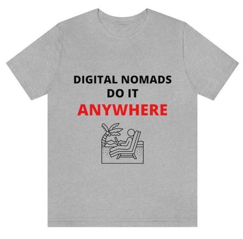 May include: Gray t-shirt with the text "DIGITAL NOMADS DO IT ANYWHERE" in black. A black and white illustration of a person sitting on a beach chair with a laptop is below the text.