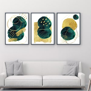 May include: Three abstract art prints with gold and teal green circles and geometric shapes. The prints are framed in black and hung on a white wall.
