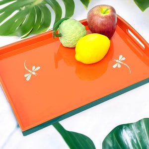 May include: Orange lacquered serving tray with a green border and dragonfly designs. The tray is filled with a lemon, a lime, and a red apple.