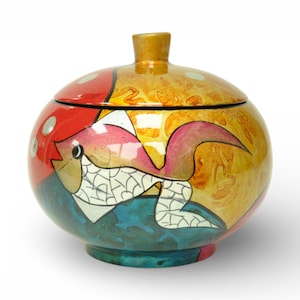 May include: A round, lidded decorative jar with a colourful fish design. The jar features a gold finial and is painted with red, yellow, blue, and pink hues. The fish has white and black details.