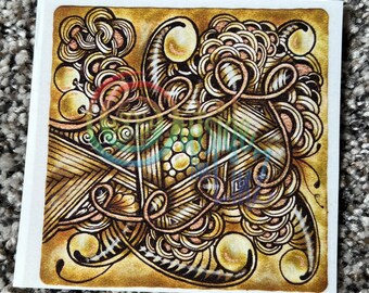 May include: Square artwork with an abstract design in shades of gold, brown, and white. The artwork features intricate patterns of lines, swirls, and geometric shapes, creating a detailed and textured appearance. The design is centered on a white square.