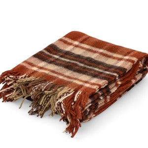 Può includere: Una coperta in lana a quadri marroni, beige e neri con frange su tutti i lati.