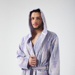 May include: A purple and white patterned bathrobe with a hood. The robe has a sash tie and a pocket on the left side.