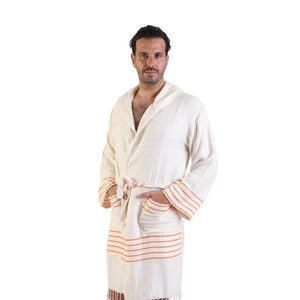 May include: A white hooded robe with orange stripes and a fringe trim. The robe is tied at the waist with a matching fabric belt.