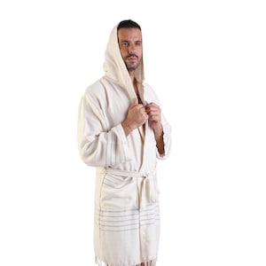 Peut inclure: Une robe blanche à capuche avec des rayures bleues et une bordure en franges. La robe est faite d'un matériau doux et absorbant, idéale pour se détendre à la maison.