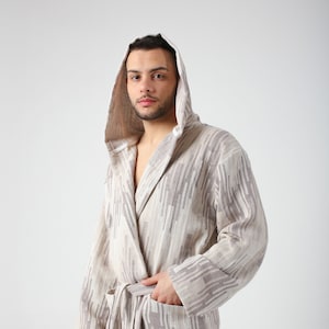 May include: A beige hooded robe with a geometric pattern in shades of brown. The robe has a sash tie and two pockets.