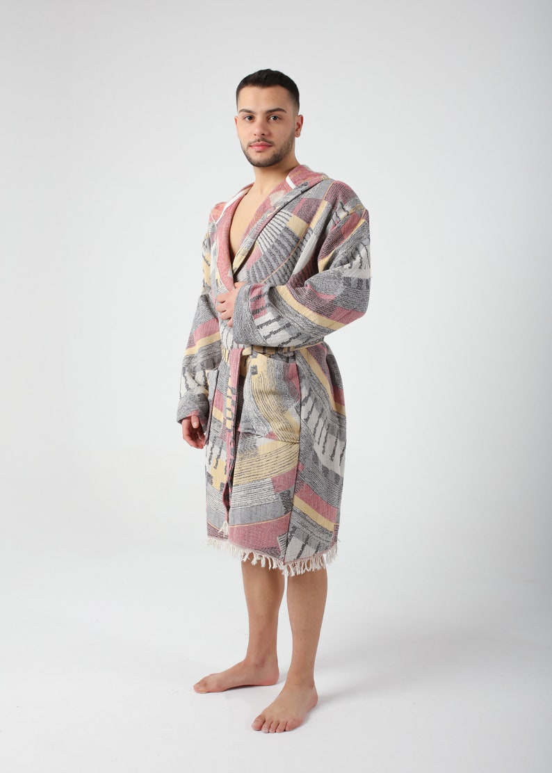 May include: A gray, pink, and yellow patterned bathrobe with a hood and a tie belt. The robe has a fringe trim.