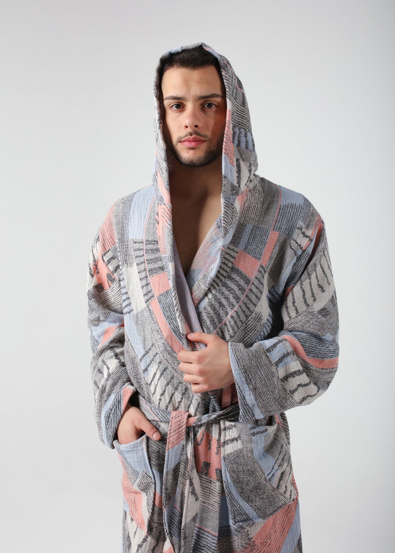 May include: A hooded robe with a geometric pattern in shades of blue, pink, and gray. The robe has a tie belt and two pockets.