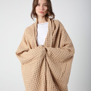 May include: A waffle-weave cardigan in a light brown color. The cardigan is open in the front and has a relaxed fit.