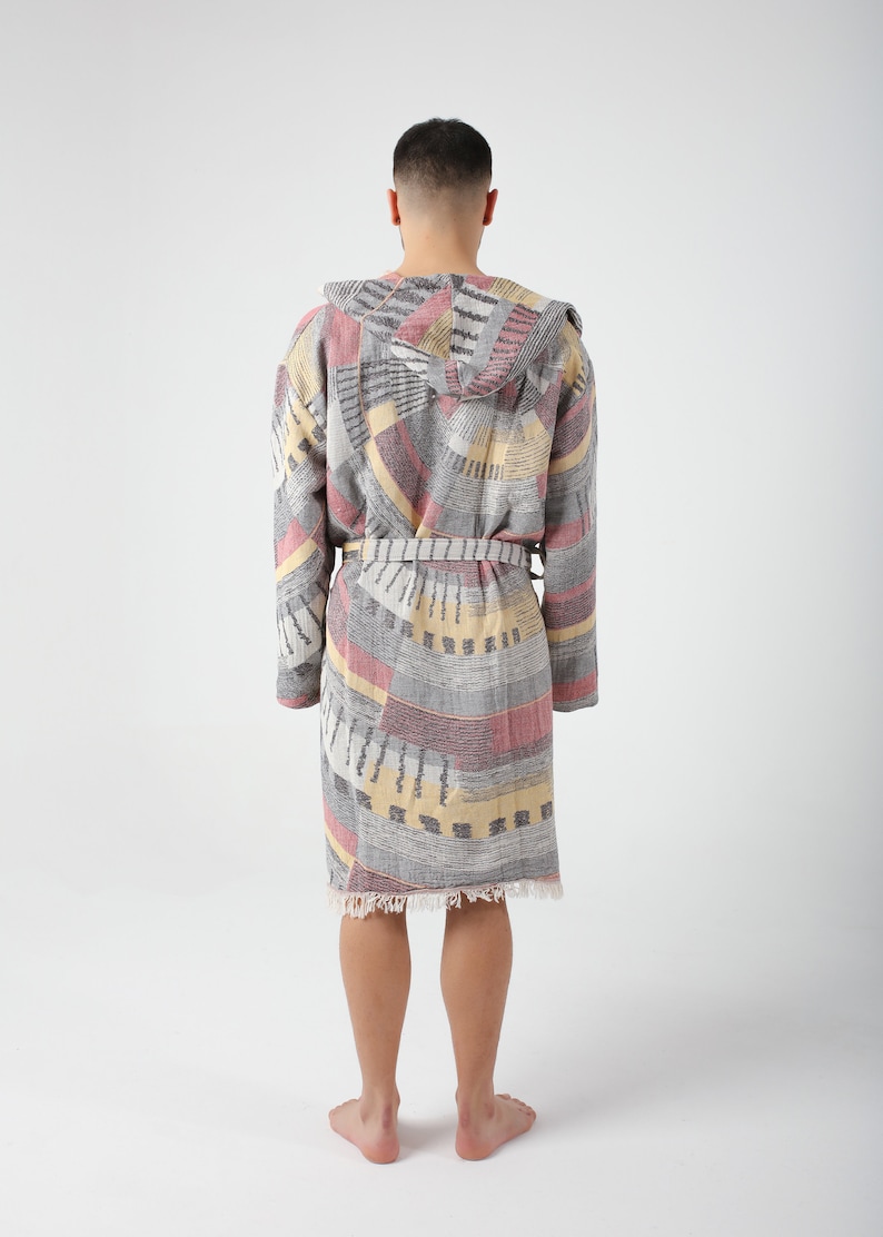 May include: A gray, pink, and yellow patterned robe with a hood and a belt. The robe has a fringed hem.
