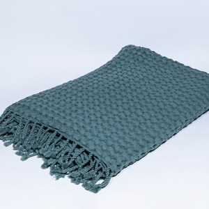 May include: A teal blue waffle weave throw blanket with a fringe border.