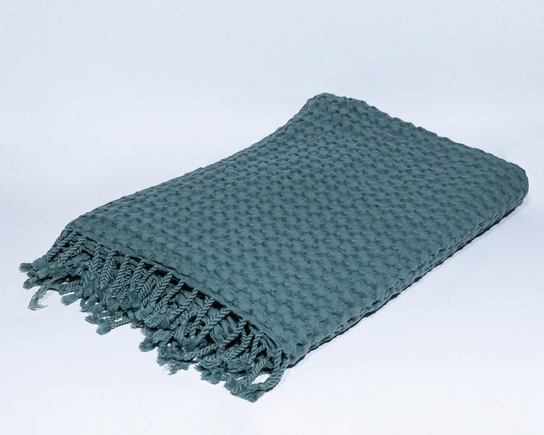 May include: A teal blue waffle weave throw blanket with a fringe border.