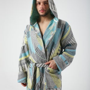 May include: A hooded robe with a geometric pattern in shades of blue, gray, and yellow. The robe has a tie belt and a pocket on the left side.