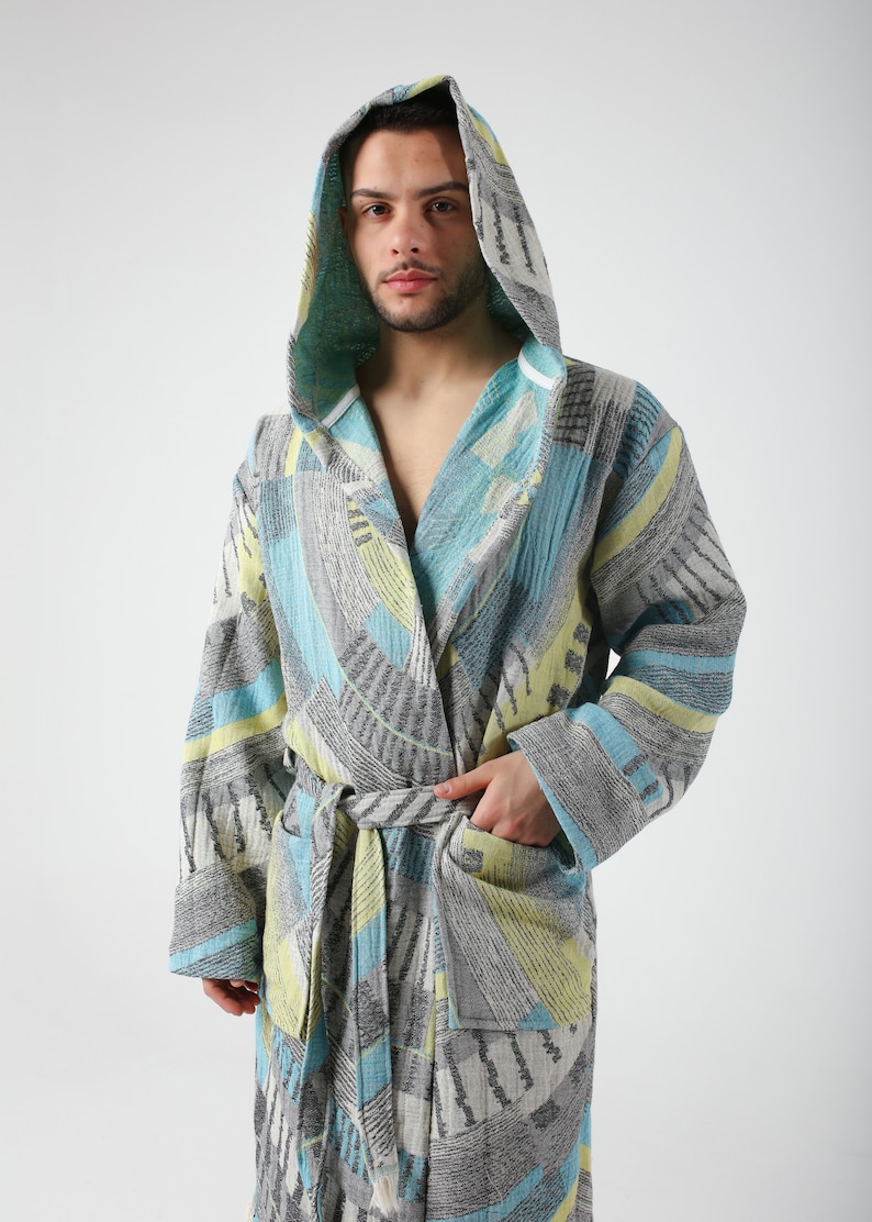 May include: A hooded robe with a geometric pattern in shades of blue, gray, and yellow. The robe has a tie belt and a pocket on the left side.