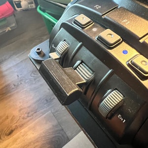 May include: Close-up of a black camera with multiple buttons and dials. The buttons are labeled "F1", "F2", "SW1", and "EM1".