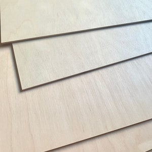 May include: Stack of four light brown plywood sheets, showing the grain of the wood.