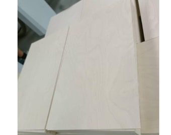 May include: Stack of light-colored wood panels, likely plywood, with a smooth, slightly textured surface.