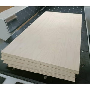 May include: A stack of thin, light wood panels, probably plywood, with a smooth, light-coloured surface. The wood has a subtle grain pattern.