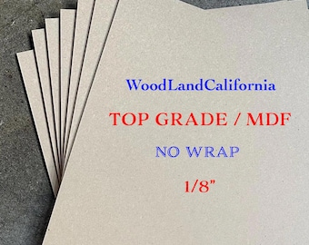 May include: A stack of light brown MDF sheets with text printed in blue and red that reads WoodLandCalifornia, TOP GRADE / MDF, NO WRAP, and 1/8 inch. The sheets are arranged in a fanned-out pattern, showing the smooth, flat surface of the material.